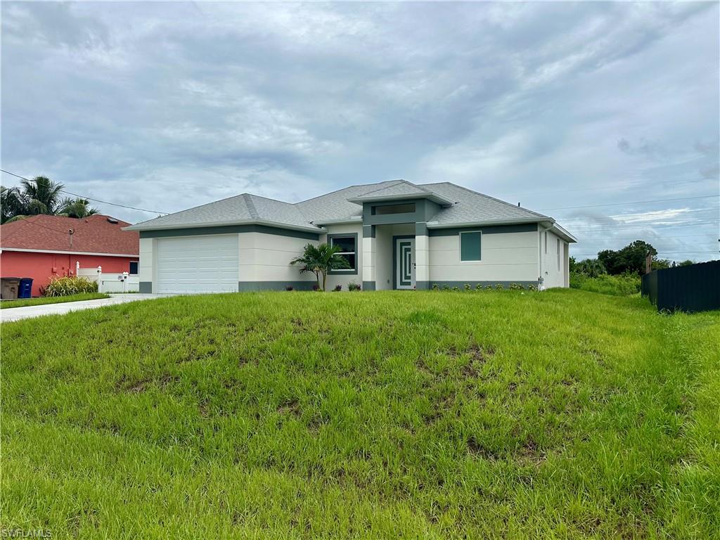 View of front facade featuring an attached garage, a front lawn, driveway, and stucco siding