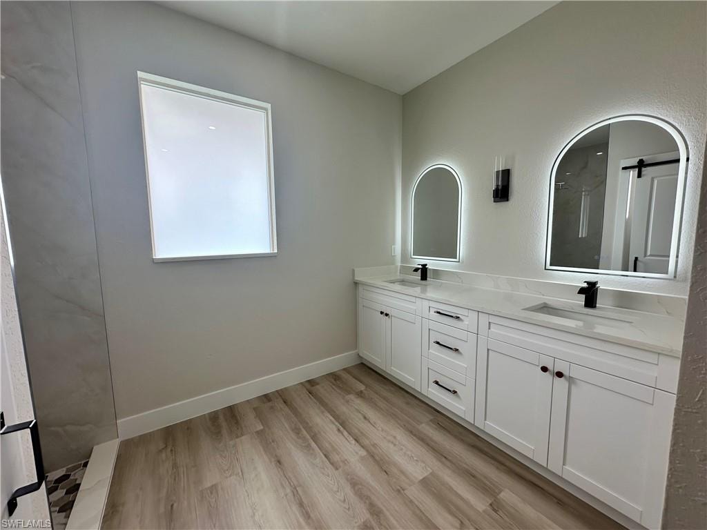 Kitchen with a barn door, crown molding, white cabinets, a large island, and recessed lighting