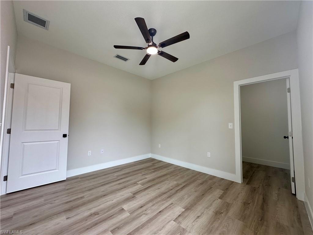 Full bath with vanity, a shower stall, a textured wall, and light wood-type flooring