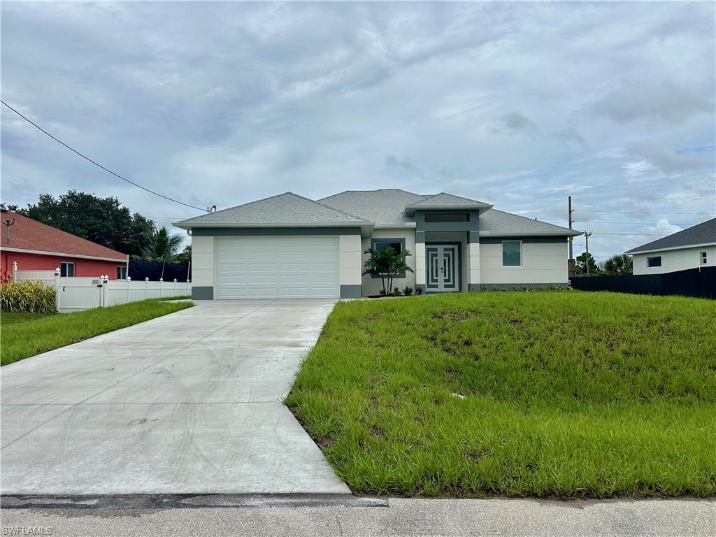 View of front of home with a garage, stucco siding, and driveway