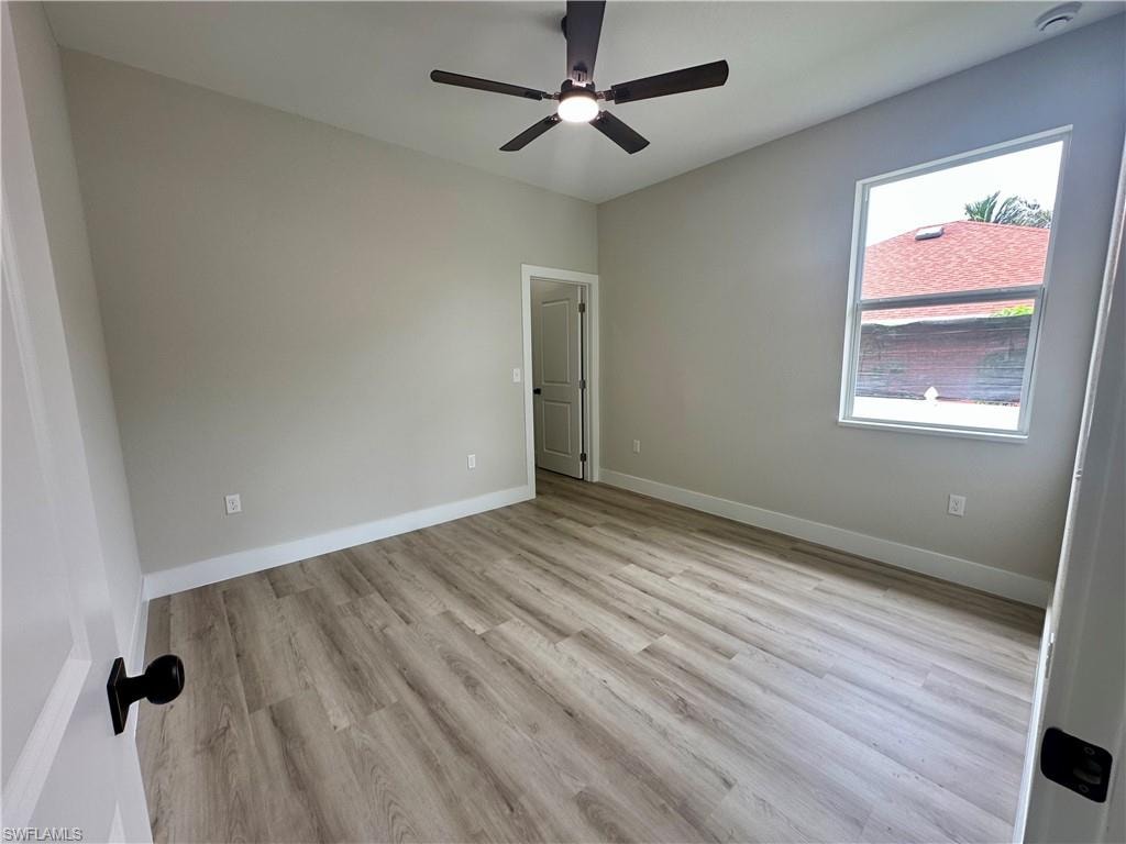 Empty room featuring a raised ceiling, light wood finished floors, recessed lighting, crown molding, and a ceiling fan