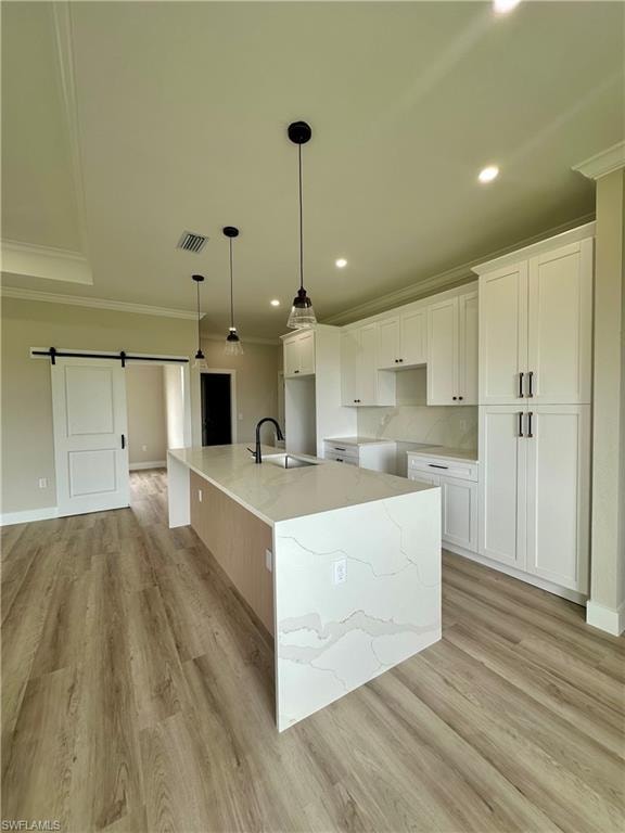 Unfurnished living room with a barn door, a raised ceiling, ceiling fan, light wood-style flooring, and recessed lighting