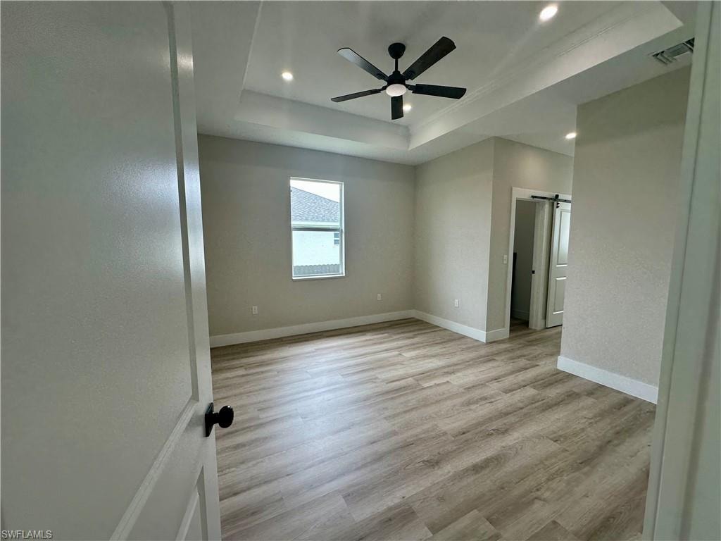 Kitchen featuring a barn door, light stone counters, crown molding, appliances with stainless steel finishes, and white cabinets