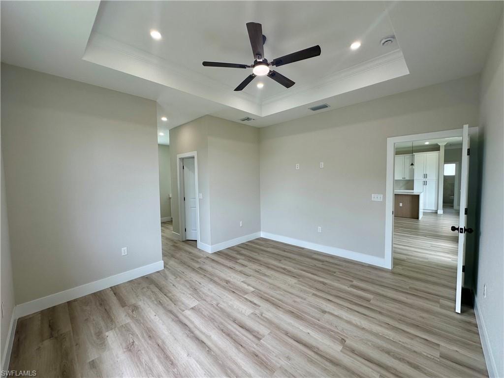 Kitchen featuring appliances with stainless steel finishes, light stone countertops, crown molding, tasteful backsplash, and light wood-style flooring