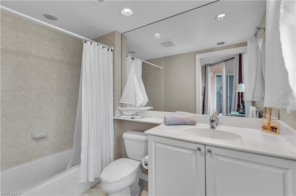 Bathroom with vanity, shower / tub combo, and recessed lighting