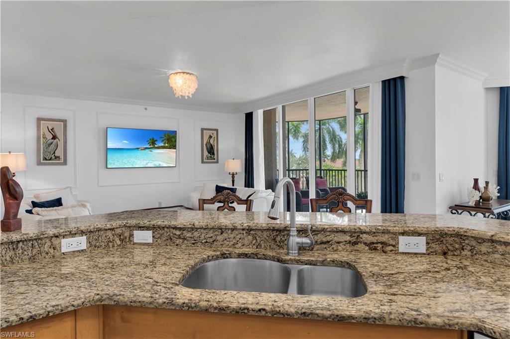 Kitchen featuring crown molding, light stone counters, open floor plan, and a chandelier