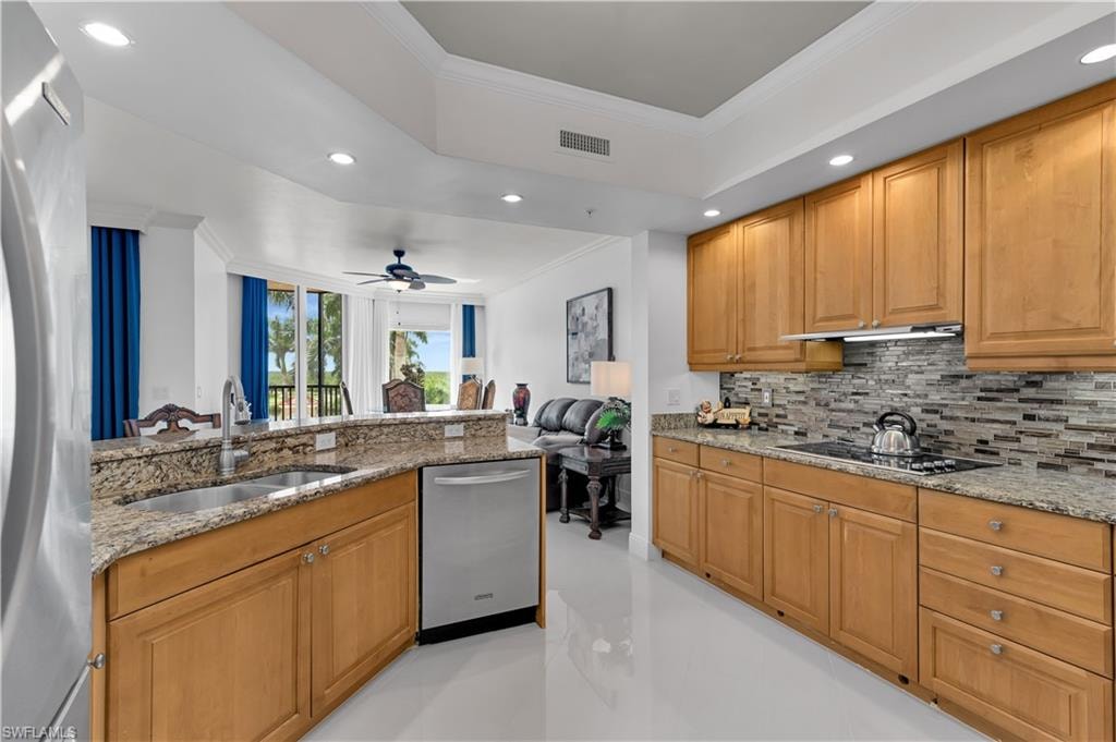 Kitchen featuring ornamental molding, recessed lighting, appliances with stainless steel finishes, light stone countertops, and a raised ceiling