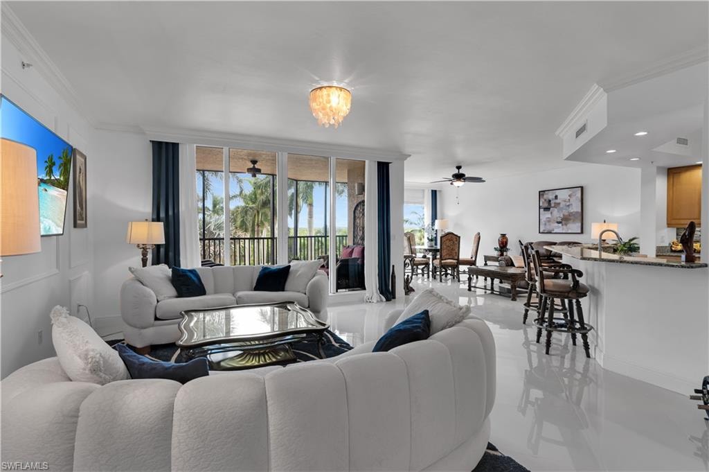 Living area featuring ceiling fan, ornamental molding, a wall of windows, and a chandelier