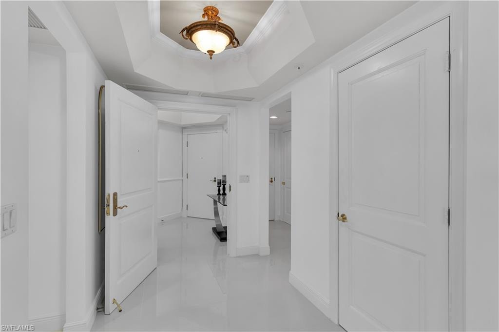 Hall featuring a tray ceiling and crown molding