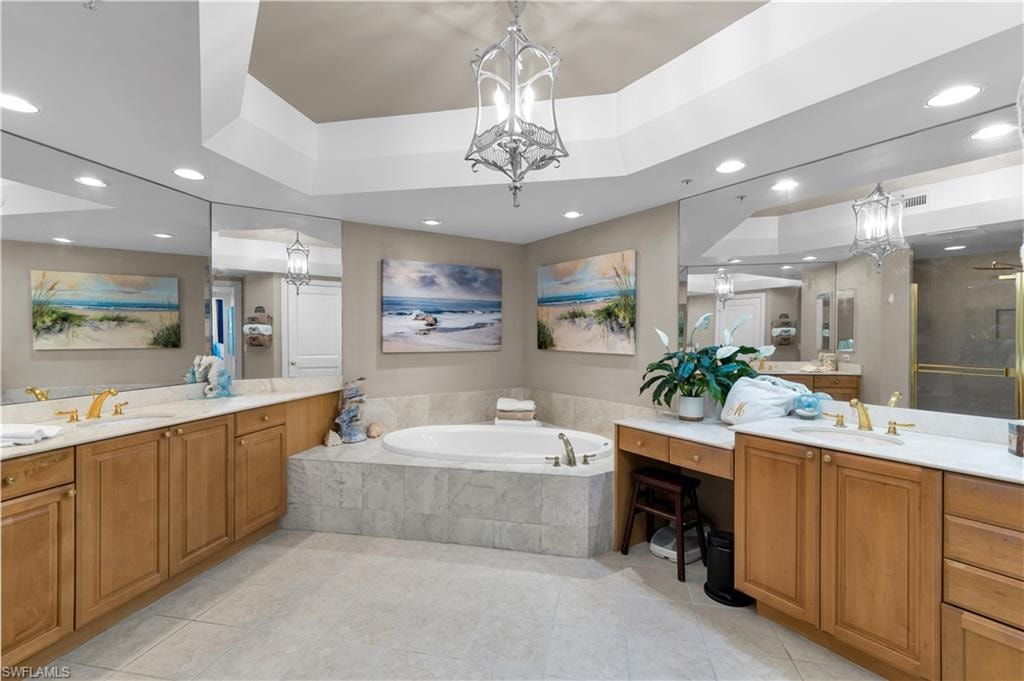 Bathroom featuring a raised ceiling, a bath, two vanities, a shower stall, and recessed lighting