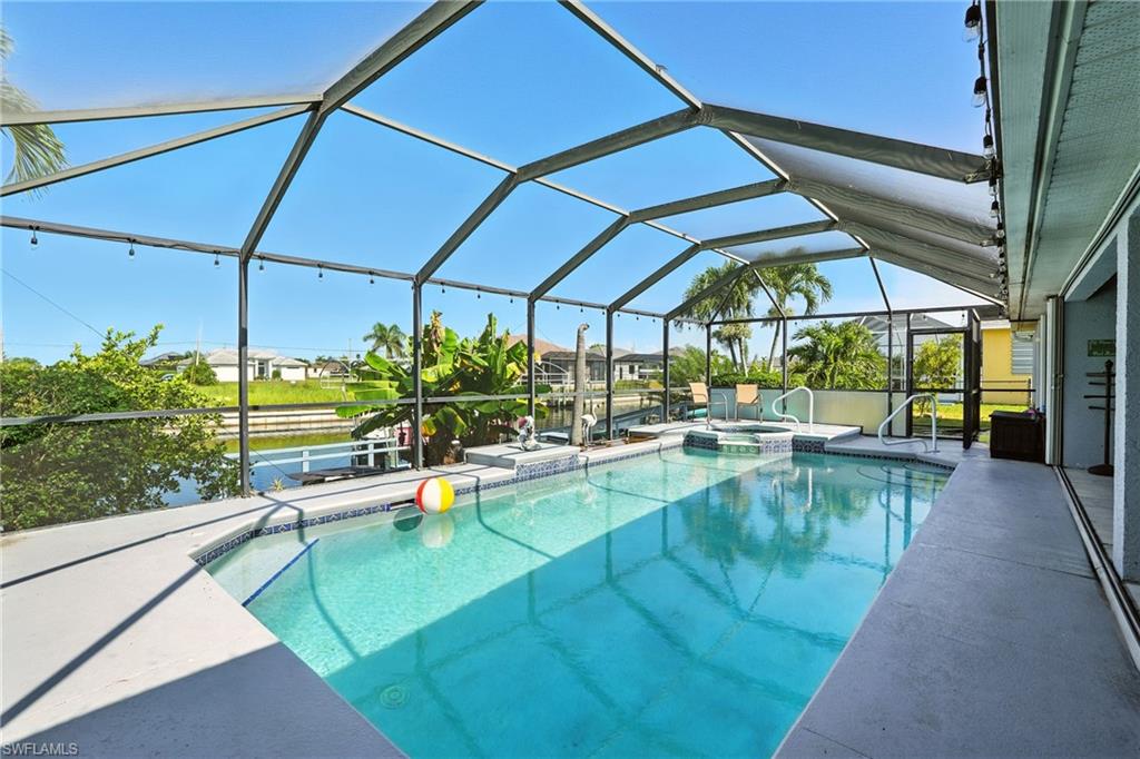 View of swimming pool featuring a lanai, a patio area, a pool with connected hot tub, a water view, and a residential view