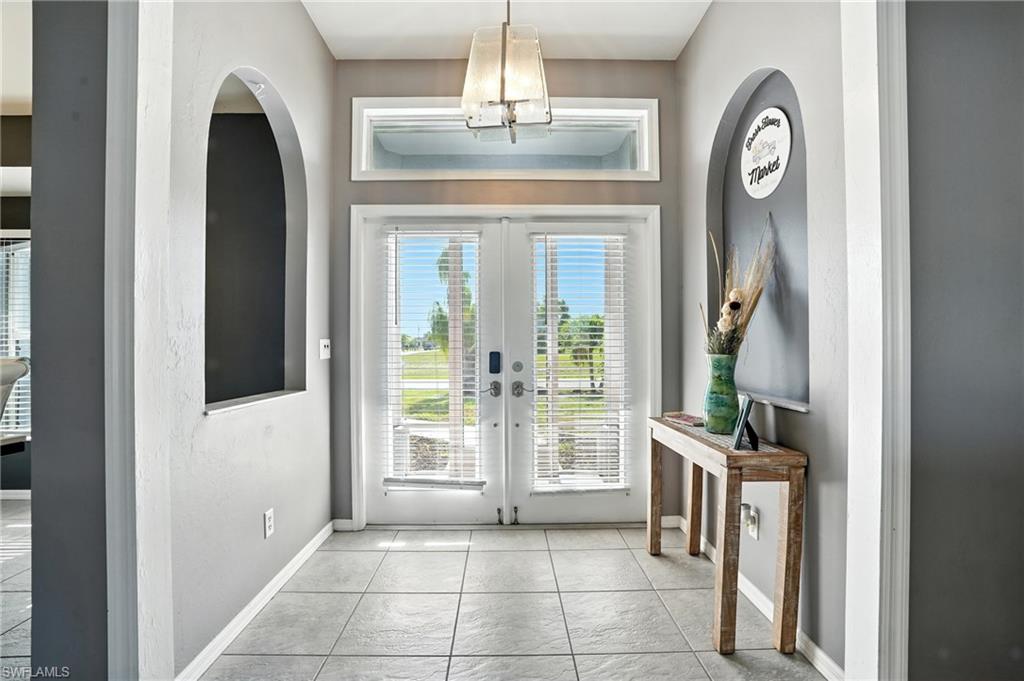 Doorway to outside featuring french doors, tile patterned floors, and arched walkways