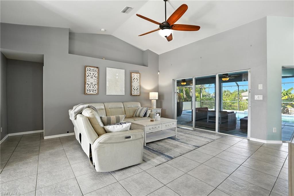 Living room featuring high vaulted ceiling, a ceiling fan, light tile patterned flooring, and a sunroom