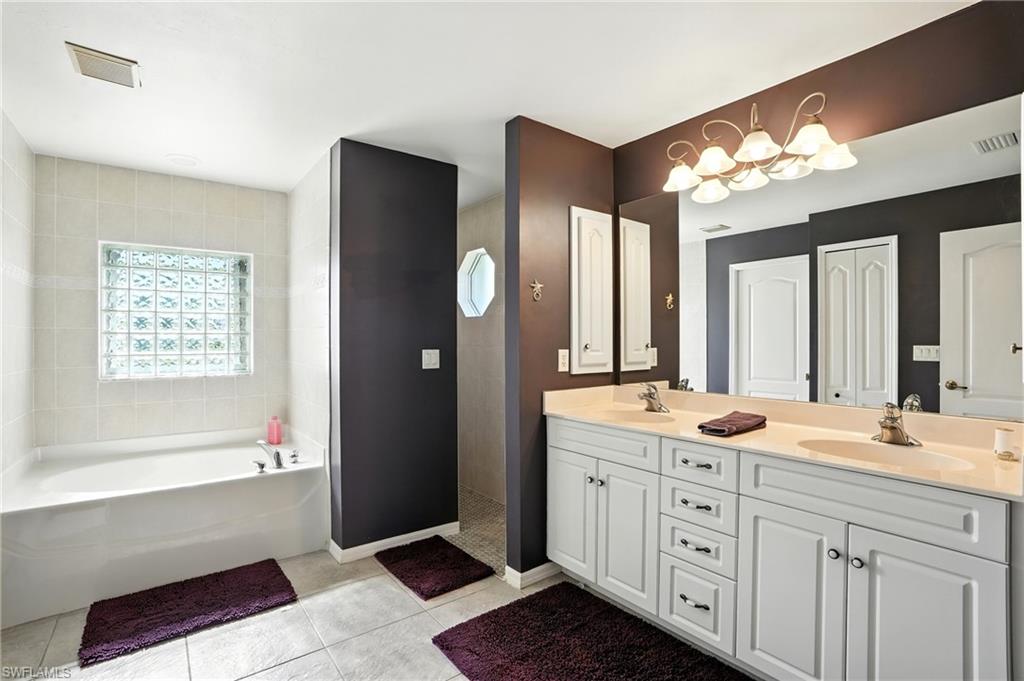 Full bathroom with tile patterned floors, a soaking tub, double vanity, and tiled shower