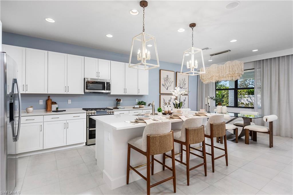 Kitchen with stainless steel appliances, light tile patterned floors, light countertops, a center island with sink, and recessed lighting