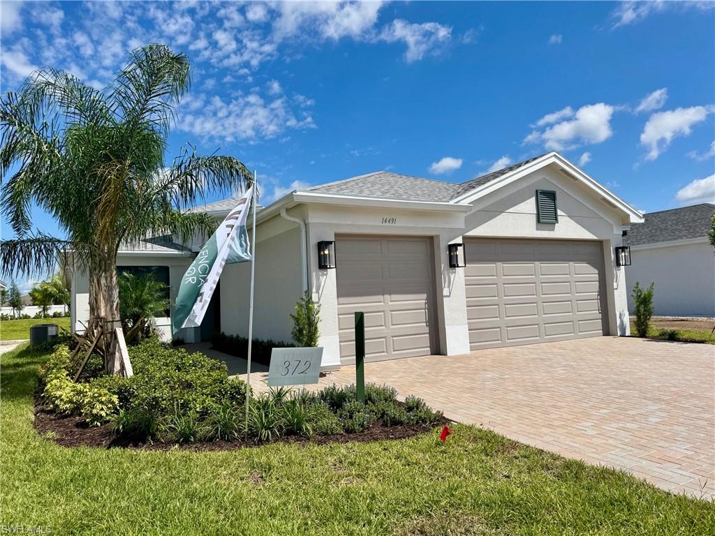 Ranch-style home featuring stucco siding, decorative driveway, an attached garage, and a front yard