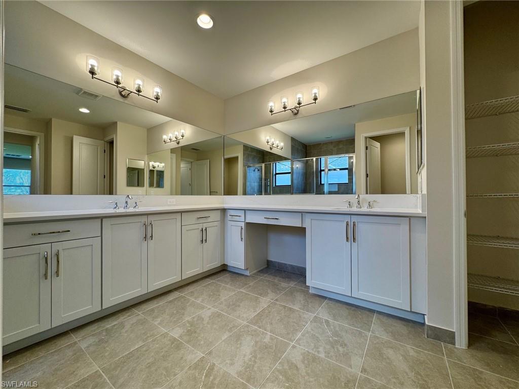 Bathroom featuring a shower stall, vanity, a spacious closet, light tile patterned flooring, and recessed lighting