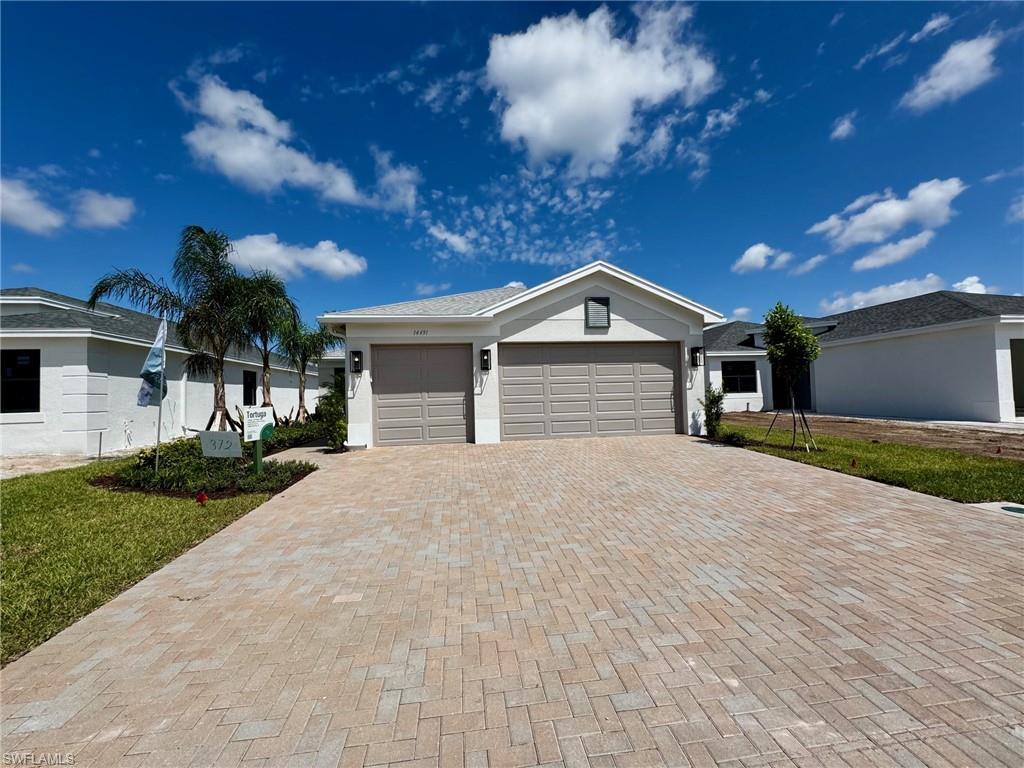 Single story home featuring decorative driveway, an attached garage, stucco siding, and a front yard