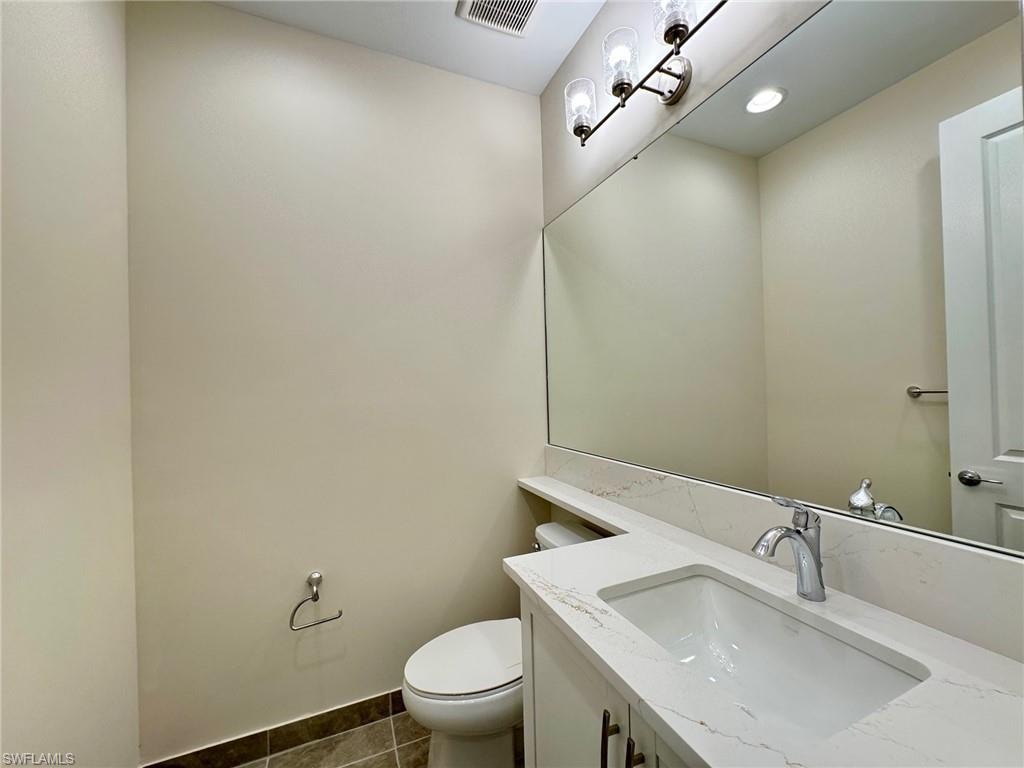 Half bath featuring vanity and dark tile patterned floors