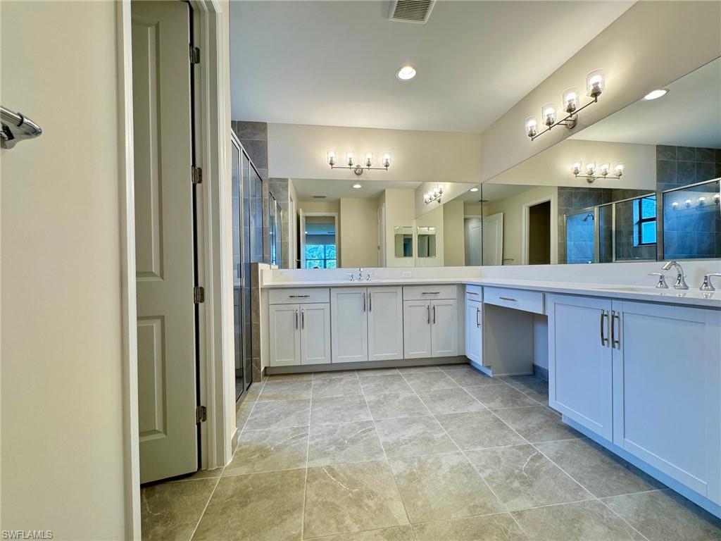 Full bathroom featuring a stall shower, two vanities, and recessed lighting
