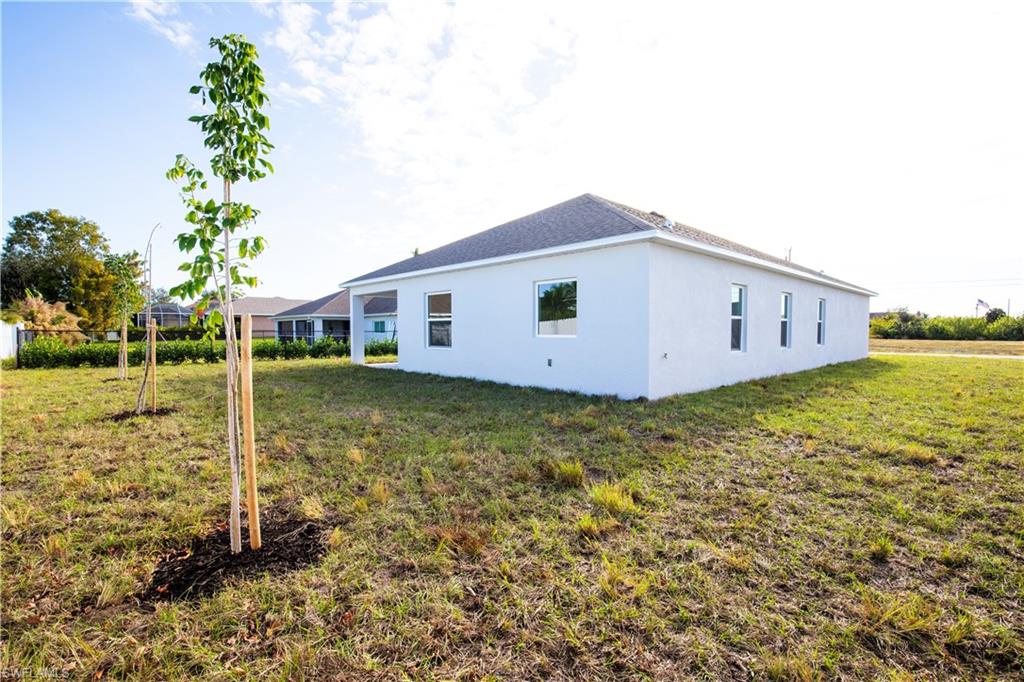 View of side of home featuring a lawn and stucco siding