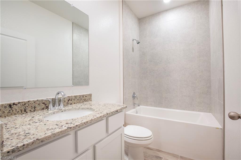 Bathroom featuring vanity, shower / bath combination, and light wood-style flooring