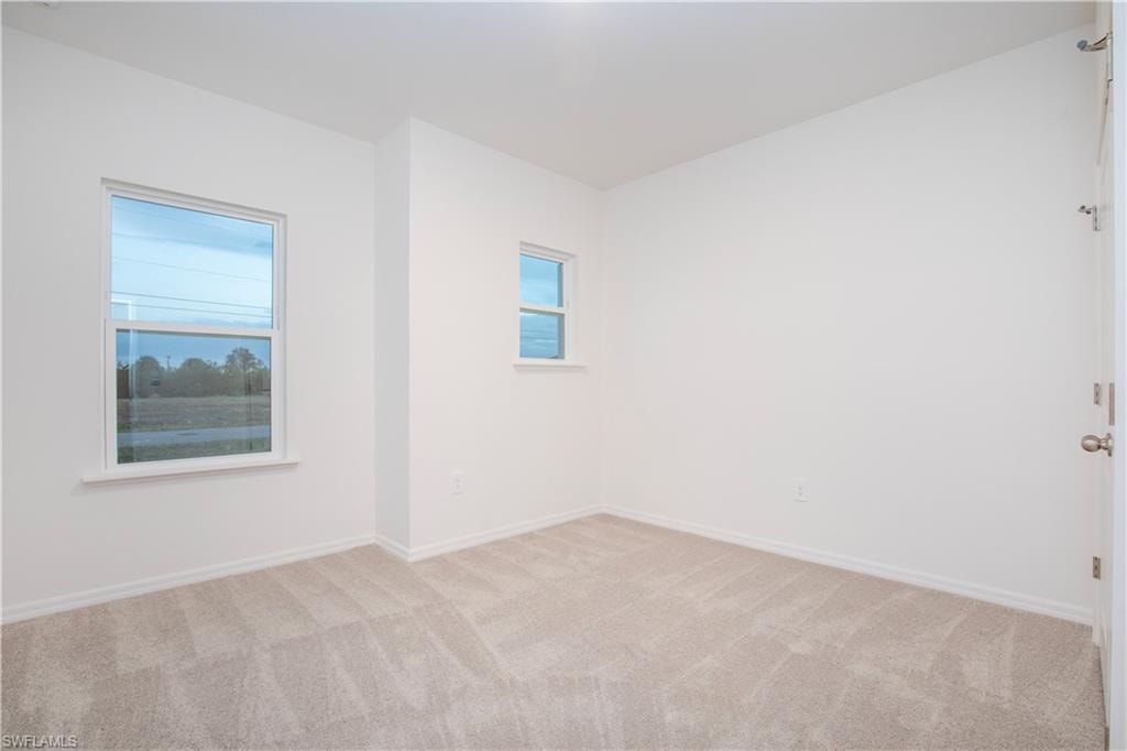 Spare room featuring healthy amount of natural light and light colored carpet