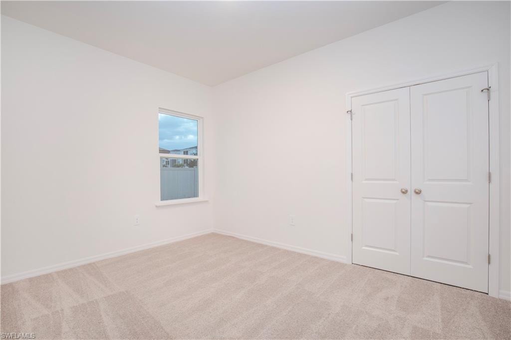Unfurnished bedroom with light colored carpet and a closet
