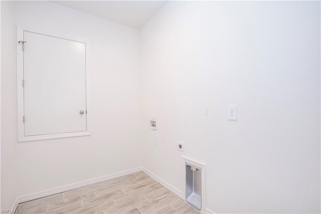Laundry area with wood finish floors, hookup for a washing machine, and electric dryer hookup