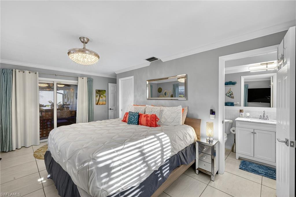 Bedroom with multiple windows, ornamental molding, light tile patterned flooring, and freestanding refrigerator