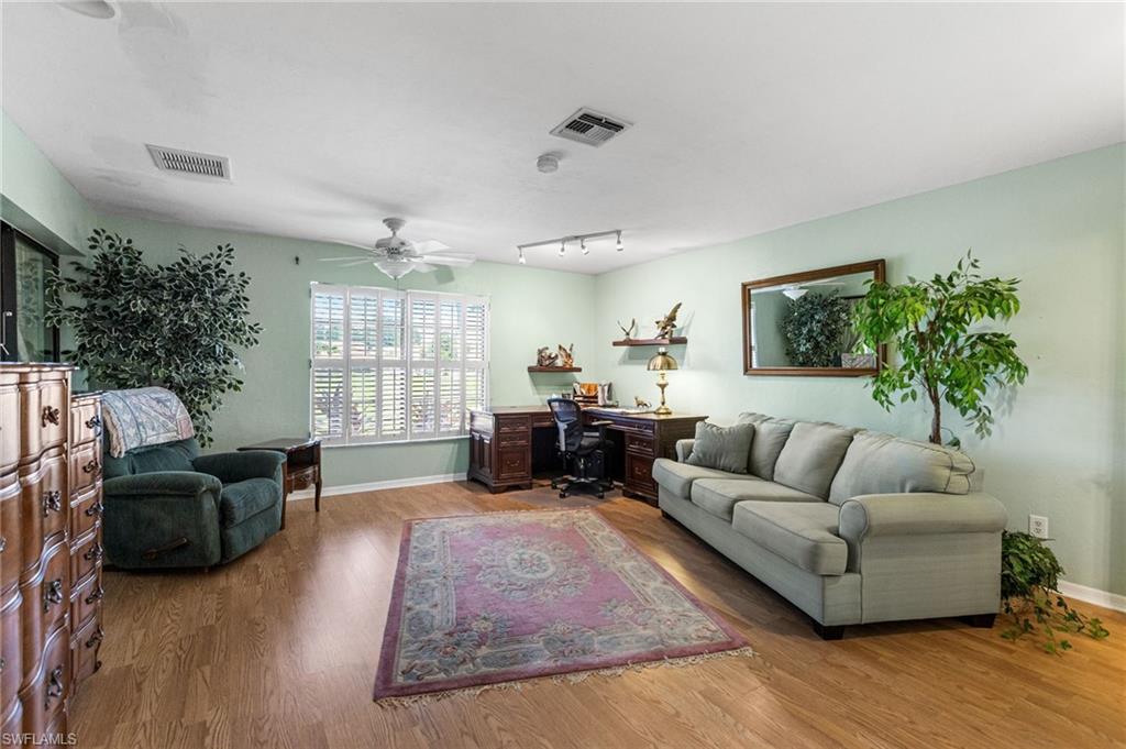 Living room featuring a desk, wood finished floors, rail lighting, and a ceiling fan