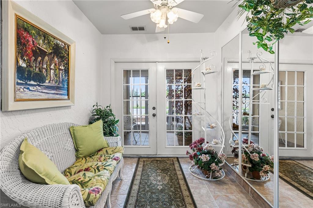 Under-air entry way styled as a Sitting room with french doors, a textured wall, and ceiling fan