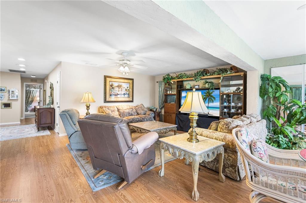 Living room with light wood-style floors, ceiling fan, and recessed lighting