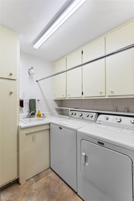 Washroom with cabinet space, washing machine and dryer, and light stone finish flooring