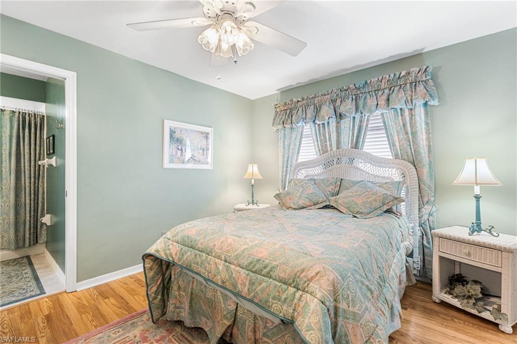 Bedroom with light wood-style floors, ceiling fan, and ensuite bathroom