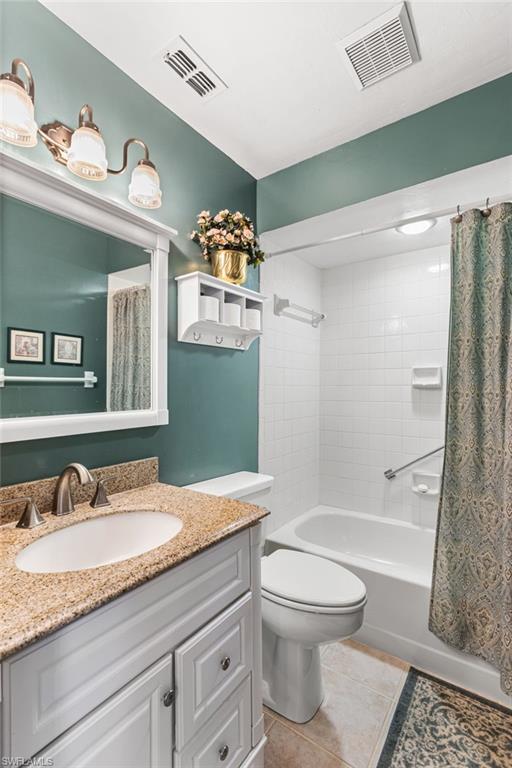 Bathroom featuring shower / bath combination with curtain, light tile patterned floors, and vanity