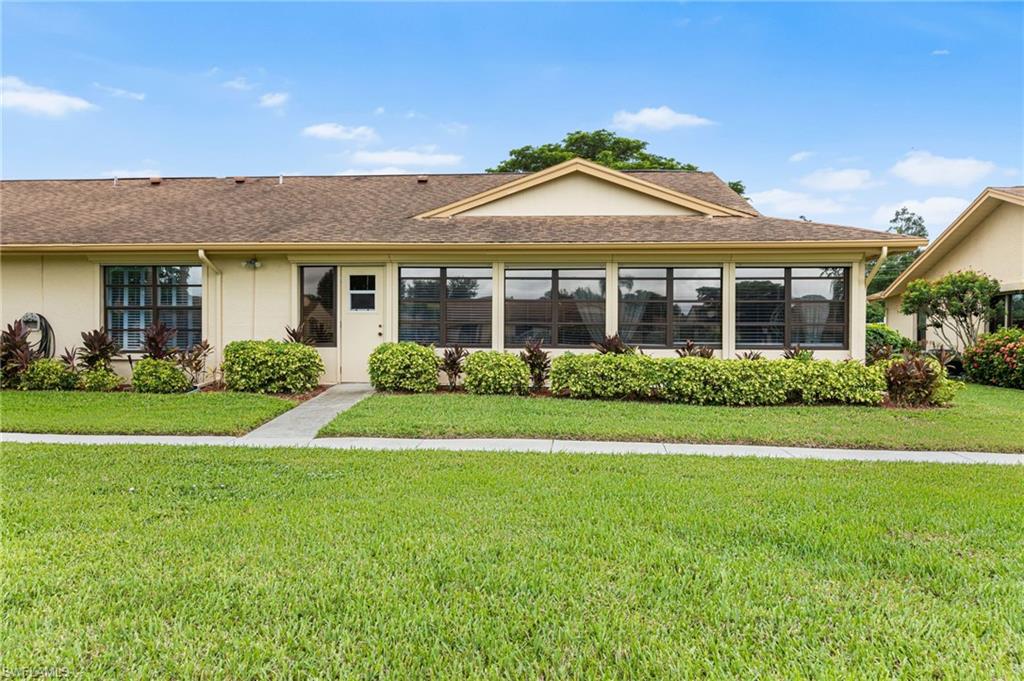 Ranch-style house featuring stucco siding, a front lawn, and a shingled roof