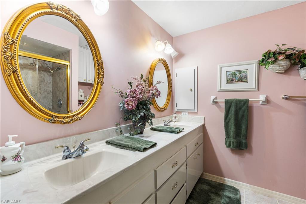 Full bath with double vanity, a shower stall, and light tile patterned floors