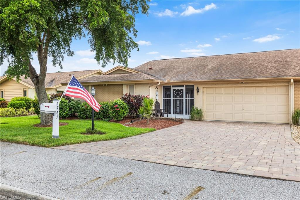 Single story home featuring decorative driveway, a garage, a front yard, roof with shingles, and stucco siding