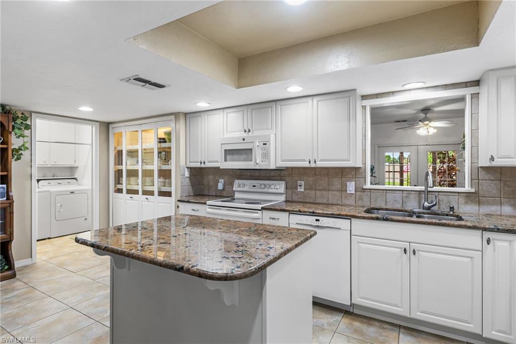 Kitchen featuring dark stone counters, white cabinetry, backsplash, and recessed lighting