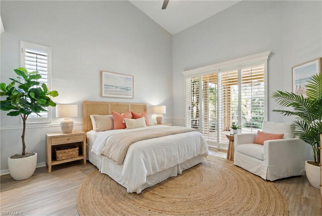 Bedroom with high vaulted ceiling, access to outside, light wood finished floors, and a ceiling fan