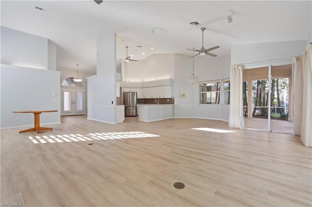 Unfurnished living room featuring french doors, light wood-style flooring, ceiling fan, and high vaulted ceiling