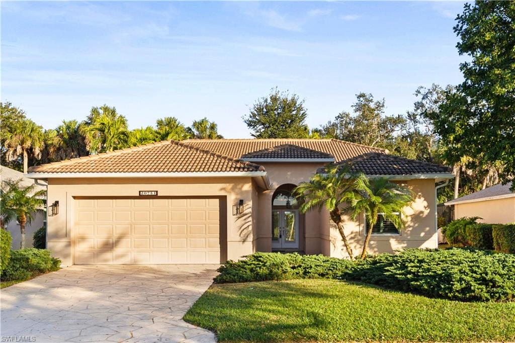 Mediterranean / spanish home with concrete driveway, stucco siding, an attached garage, a tiled roof, and a front yard