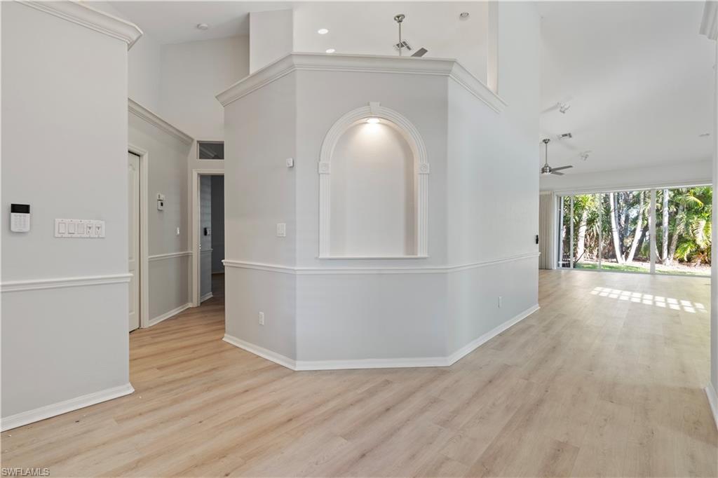 Hall featuring light wood-style flooring and a high ceiling