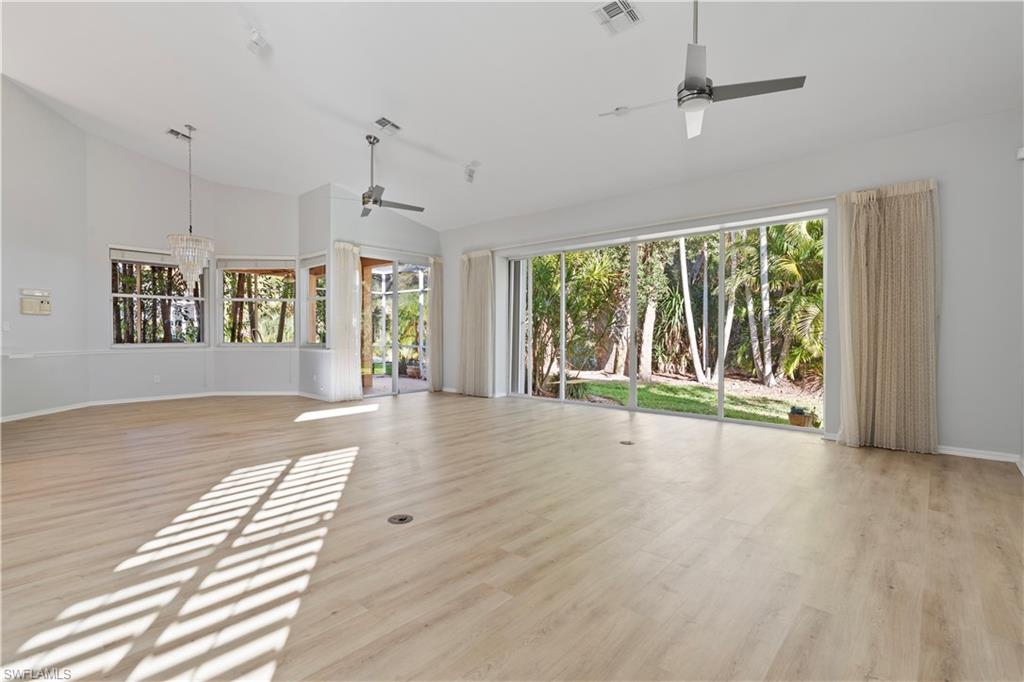Unfurnished living room with light wood-type flooring, ceiling fan, a chandelier, and high vaulted ceiling