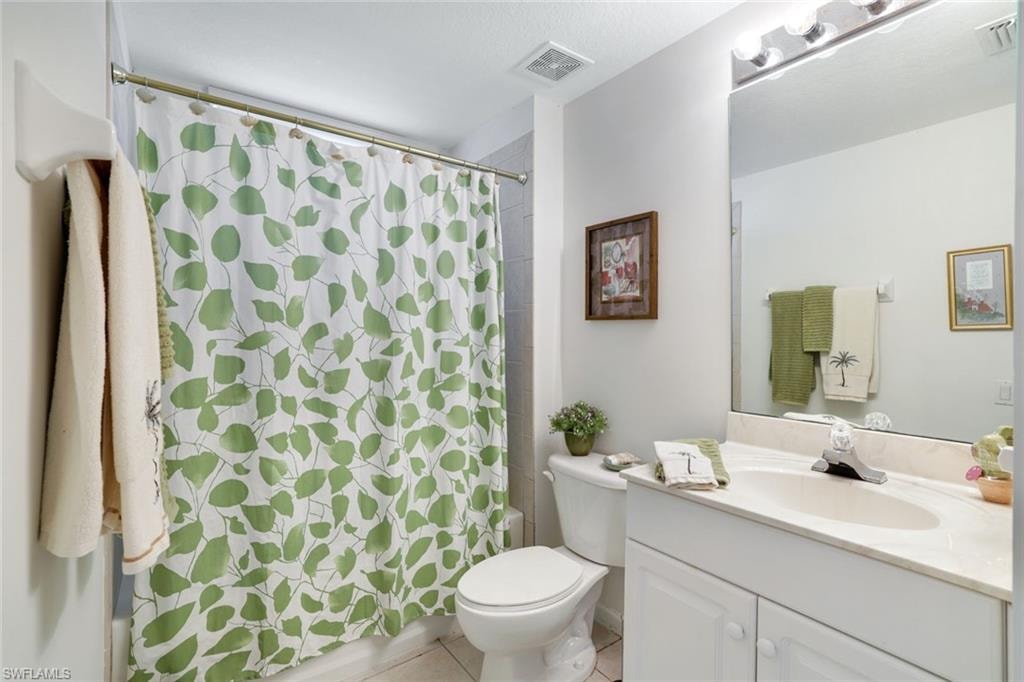 Full bath featuring vanity, light tile patterned flooring, and shower / bath combination with curtain
