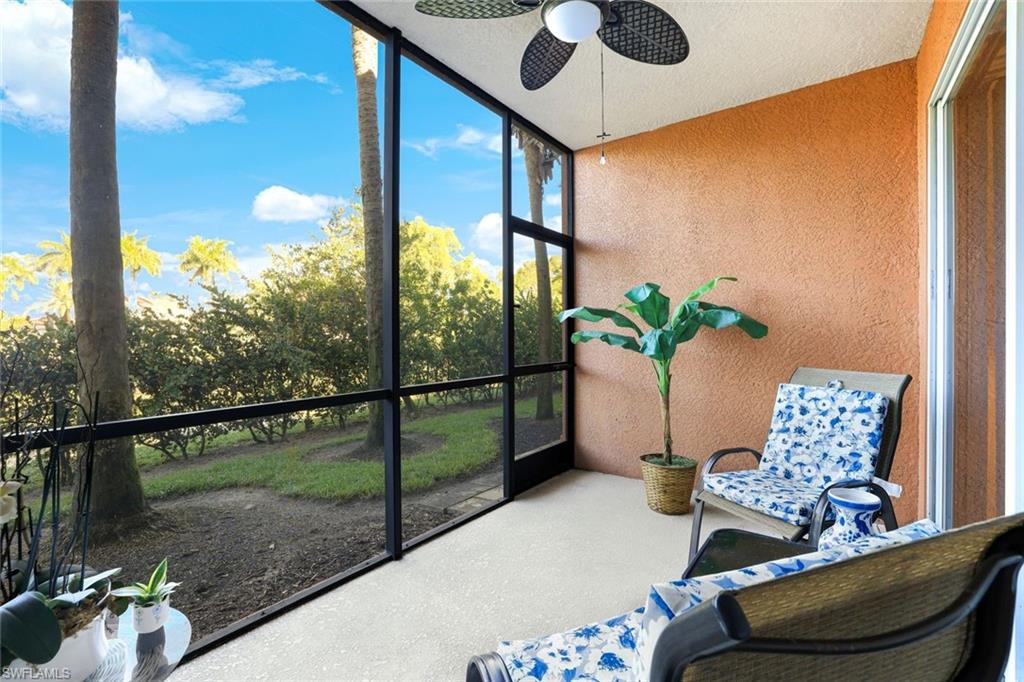 Unfurnished sunroom featuring a ceiling fan and view of wooded area