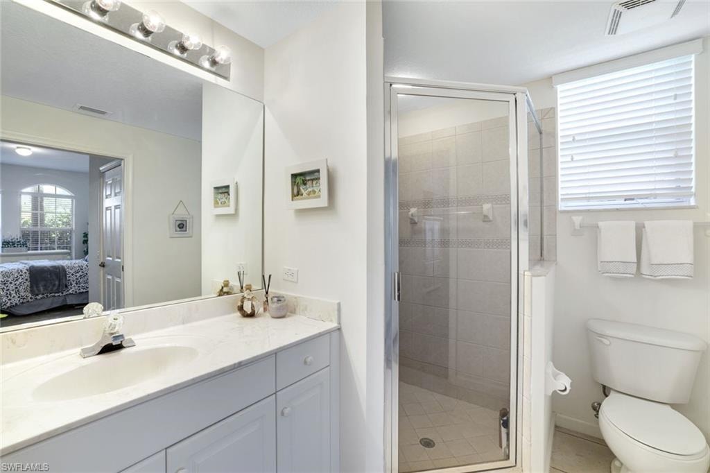 Ensuite bathroom with vanity, a stall shower, and light tile patterned floors