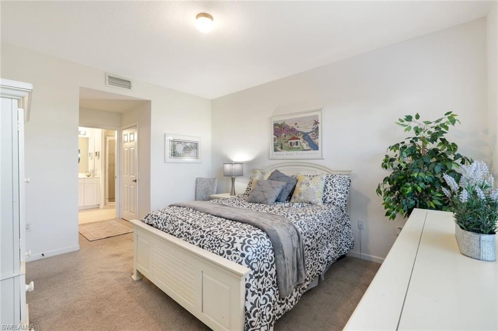Carpeted bedroom featuring ensuite bath and baseboards