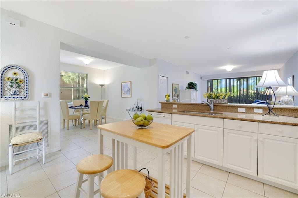 Kitchen with white cabinets, light tile patterned flooring, healthy amount of natural light, and light stone counters